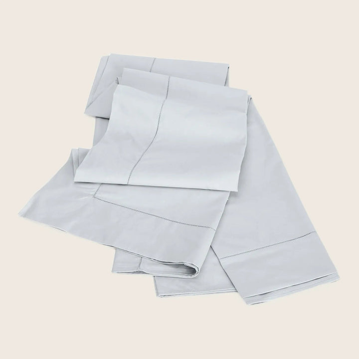 Neatly folded light gray bed linens showcasing modern luxury design.