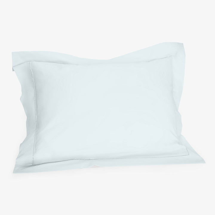 Soft white pillow on white background with visible creases.