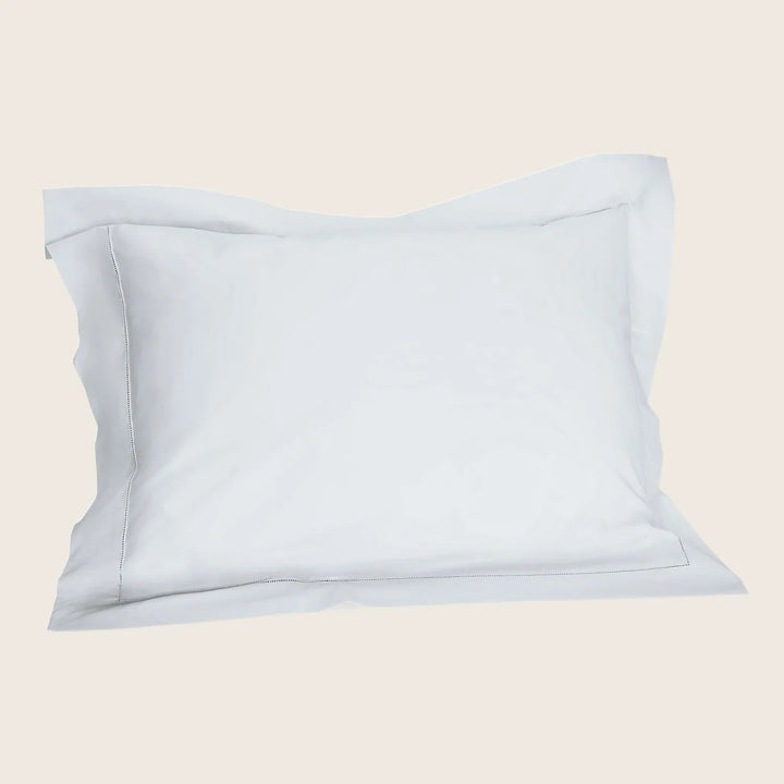 Crisp white pillowcase with stitched hem on smooth fabric.