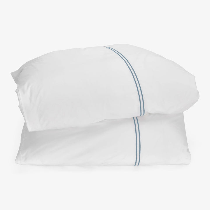 Two white pillows with blue line design elements on hem.