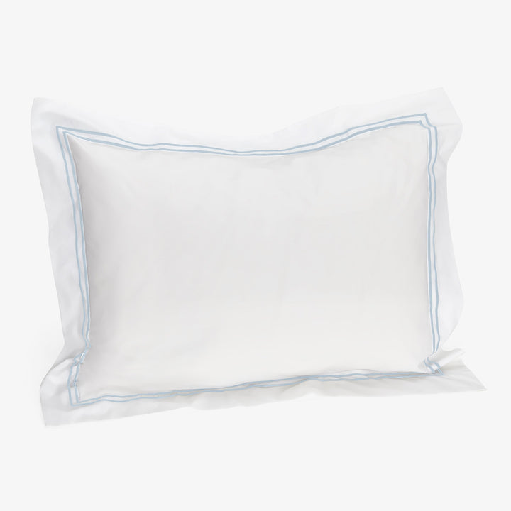 White pillow with light blue border, soft and pliable design.