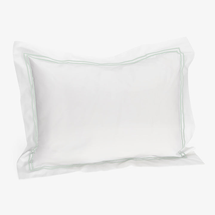 Elegant white pillowcase with green piping border for standard bed.