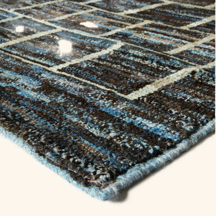 Close-up of plush geometric rug with blue, black, beige colors.