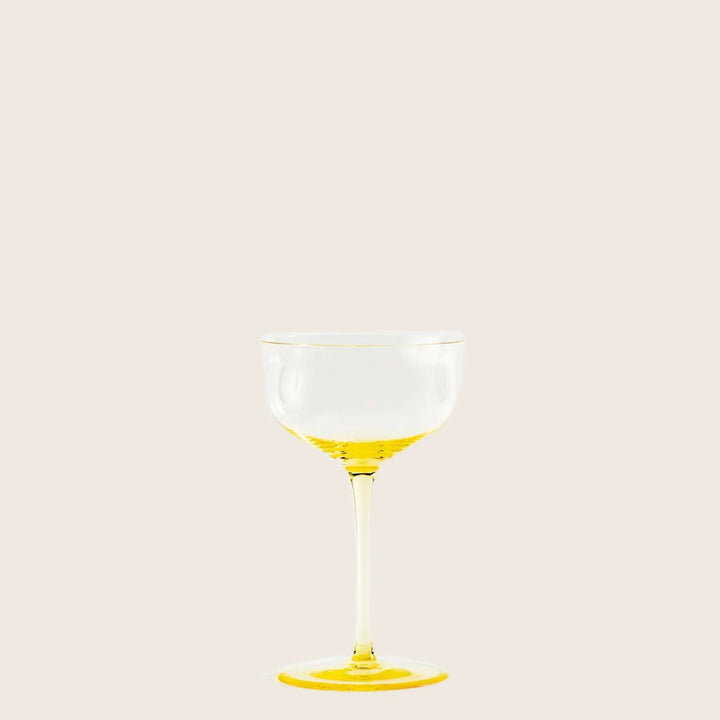 Yellow stemmed glass with liquid, part of stemware set.