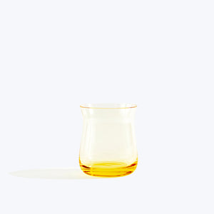 Modern clear glass pitcher with yellow tint, minimalistic setting.