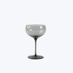 Elegant stemmed glass with smoky tint, minimalist background, polished sheen.