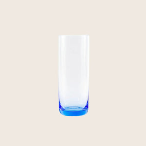 Empty tall glass with blue base against white minimalist background.