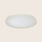 Simple oval-shaped plate with slightly elevated edge on white background.