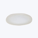 Plain white oval plate with raised edge on white background.