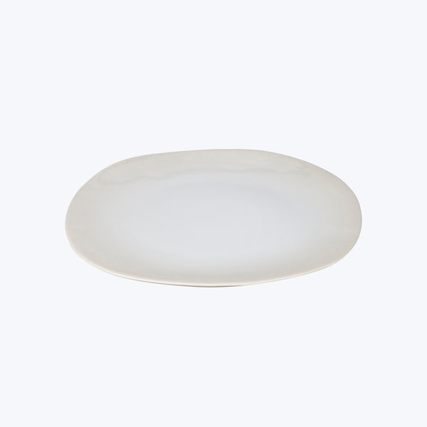 Plain white oval plate with raised edge on white background.