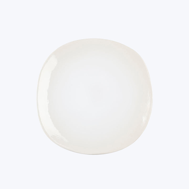 Minimalist white plate with irregular edge against white background.