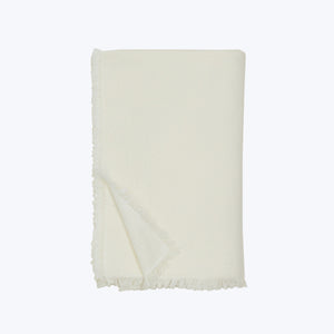 Light-colored throw with fringe on neutral backdrop, simple design.