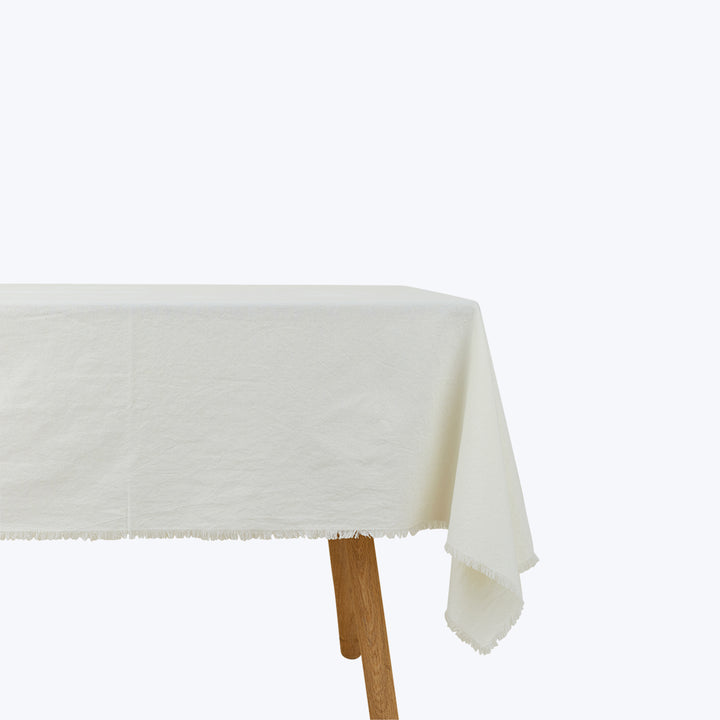 Wooden table with off-white tablecloth against white background.