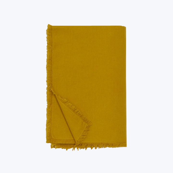 Cozy yellow textile with fringed edges on white background.