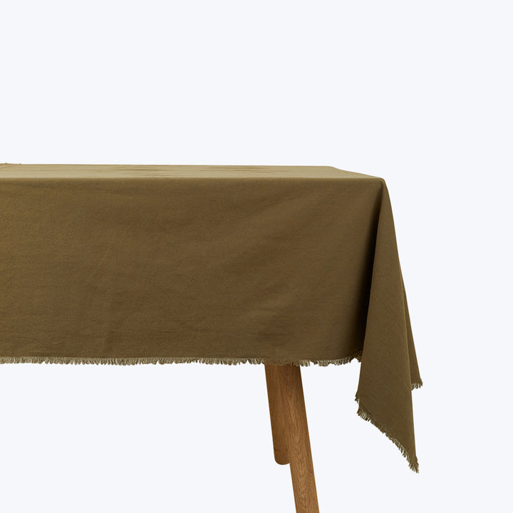 Rustic wooden table corner with textured tablecloth and frayed edge.