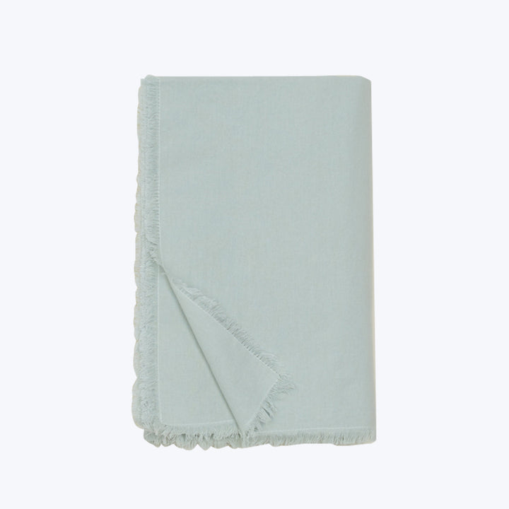 Light blue textile folded with frayed edges on white background.