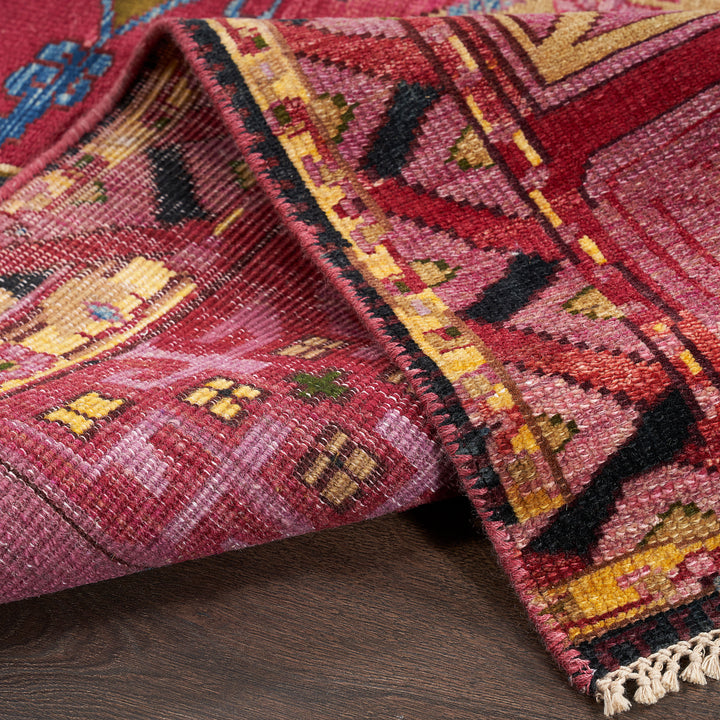 Intricately designed rug with geometric pattern in vivid colors and fringe.