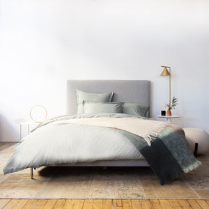 Neatly folded light gray bedding set on white background display - hover