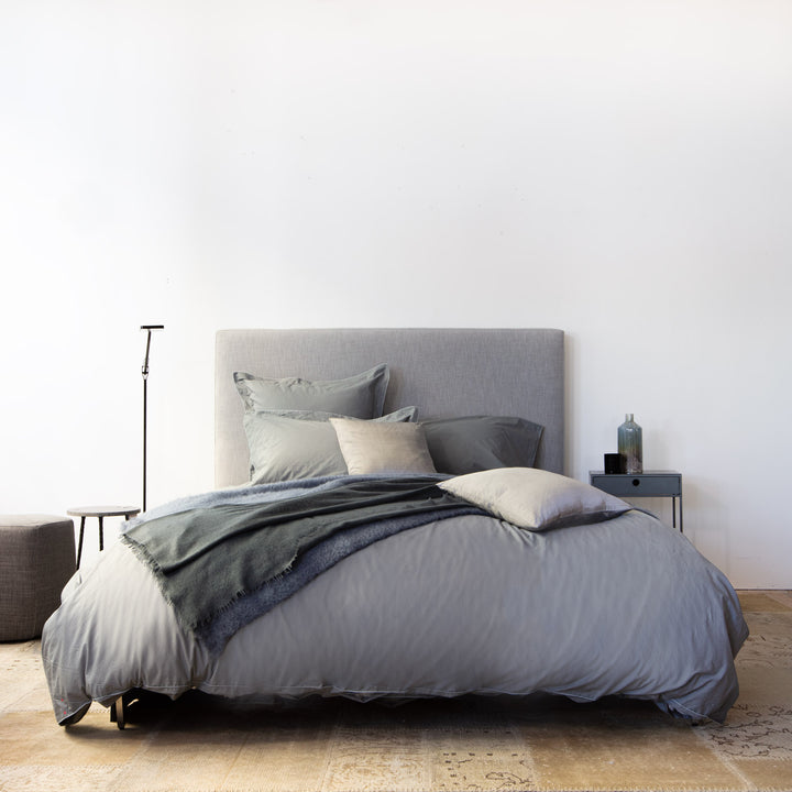 Minimalistic bedroom with grey bedding, modern decor, and serene ambiance.