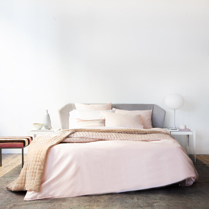 Modern bedroom with blush pink decor, minimalist style, cozy textures.
