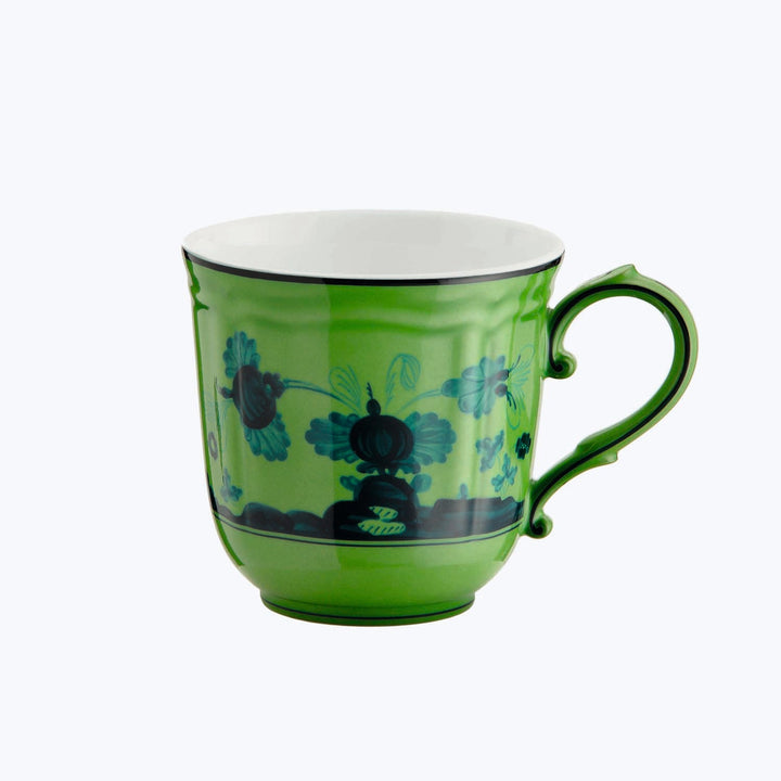 Colorful green floral tea cup with handle on right side.