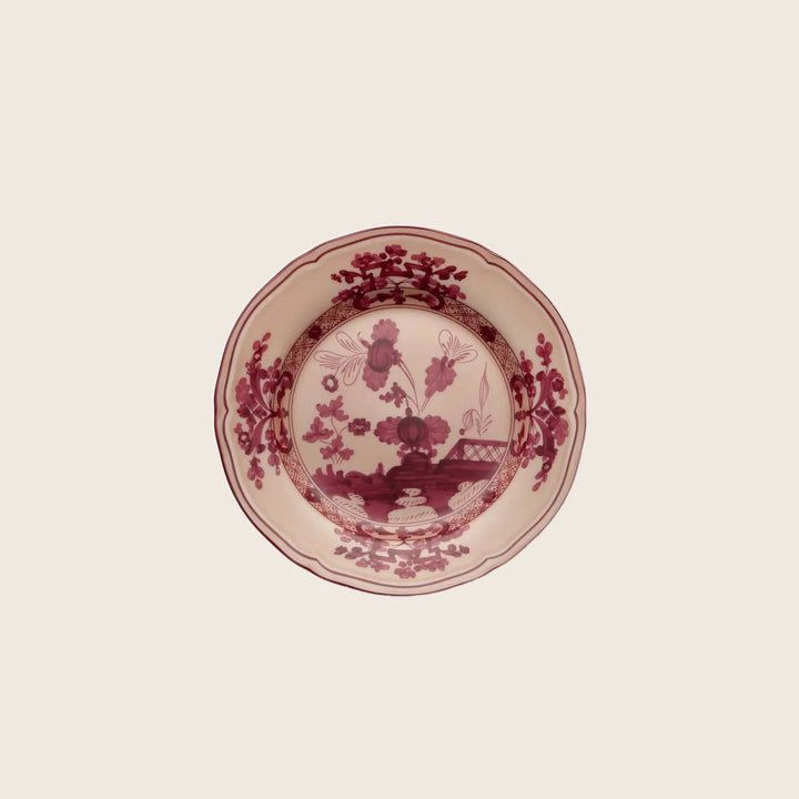 Traditional red transferware ceramic plate with intricate pastoral design.