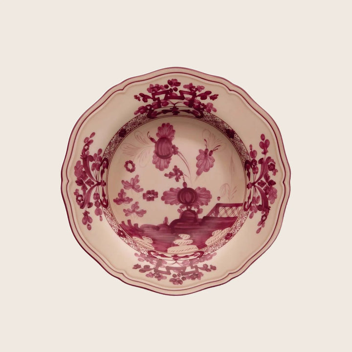 Traditional red floral ceramic plate with scalloped edge, top-down view.