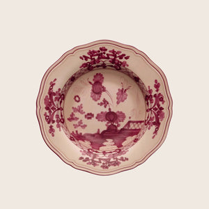 Traditional red floral ceramic plate with scalloped edge, top-down view.
