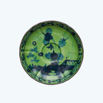 Vibrant decorative plate with blue floral pattern on green background.