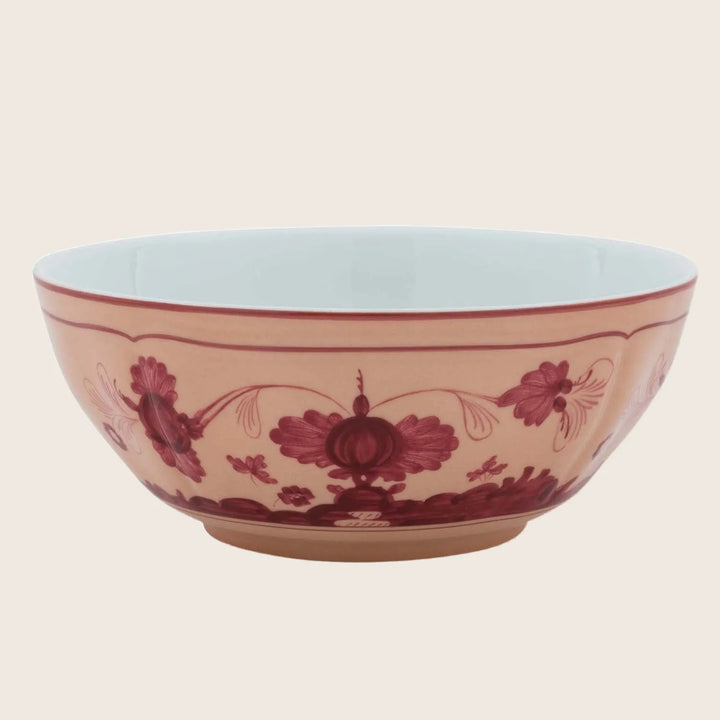 An intricately designed ceramic bowl with a peach exterior and floral motifs.