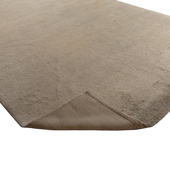 Close-up of soft, fluffy beige carpet with ribbed underside.