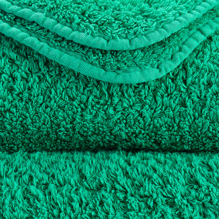 Close-up of textured green material with deep pile. Soft and intricate.