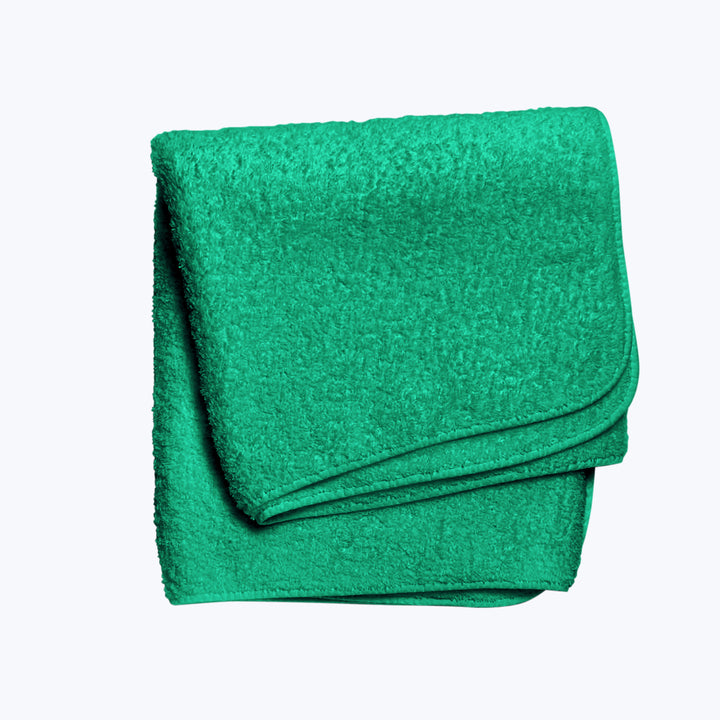 Bright turquoise terry cloth towel neatly folded against white background.