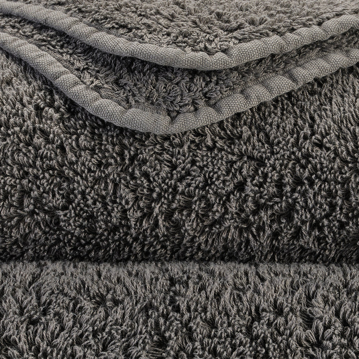Stack of fluffy grey blankets with shaggy texture and woven border.
