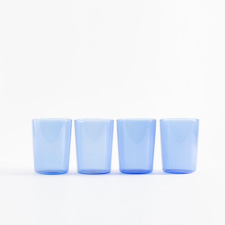 Four blue tinted glasses arranged in a minimalist style setting.