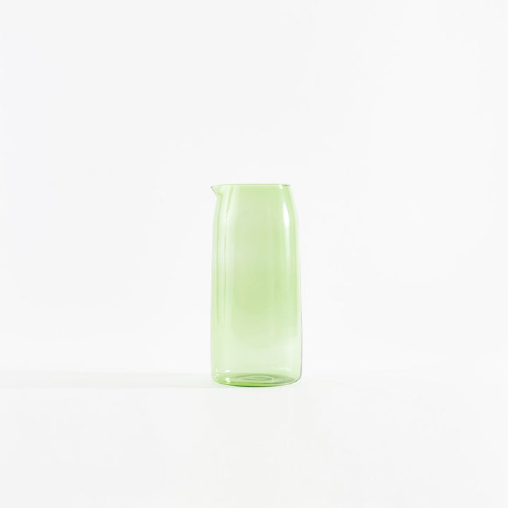 Simple green glass jug on white background, smooth and translucent.