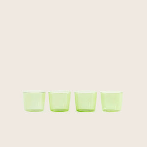 Four green translucent shot glasses arranged in a straight line.