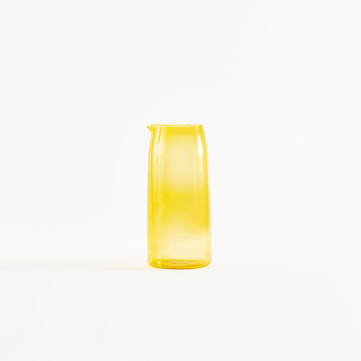 Yellow transparent pitcher with modern design on white background.