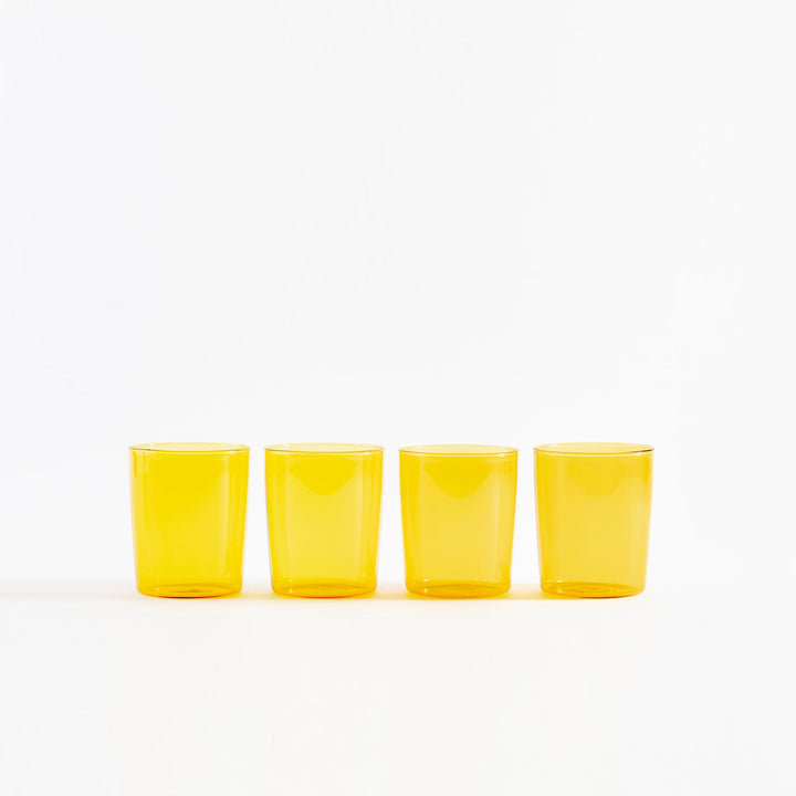 Four yellow translucent glasses aligned on white background, minimalist design.