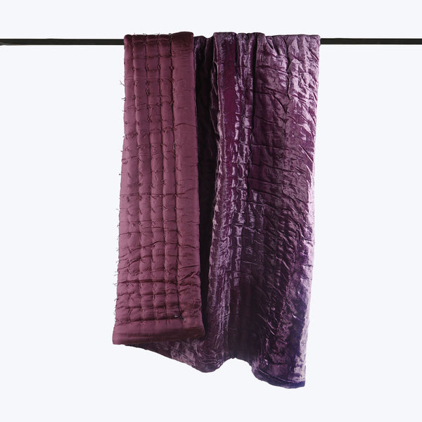 Luxurious purple curtains with textured surfaces hanging on rod.