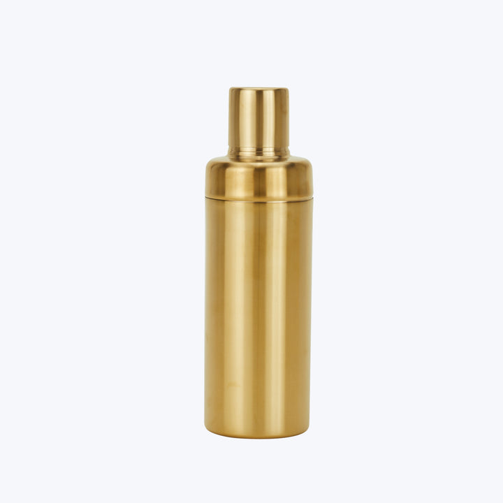 Metallic gold cocktail shaker with lid and strainer on white
