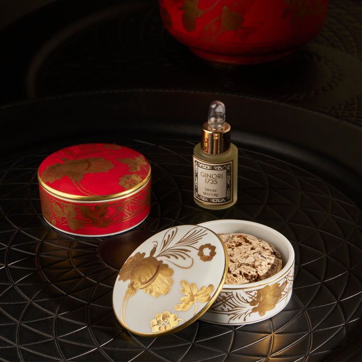 Luxury items with gold floral patterns on black textured surface.