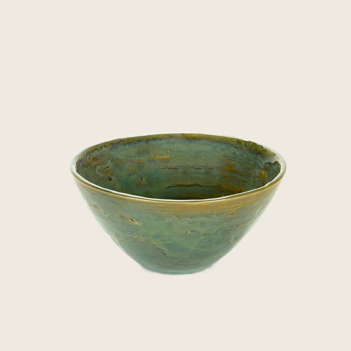 Green glazed ceramic bowl with rustic look on white background.
