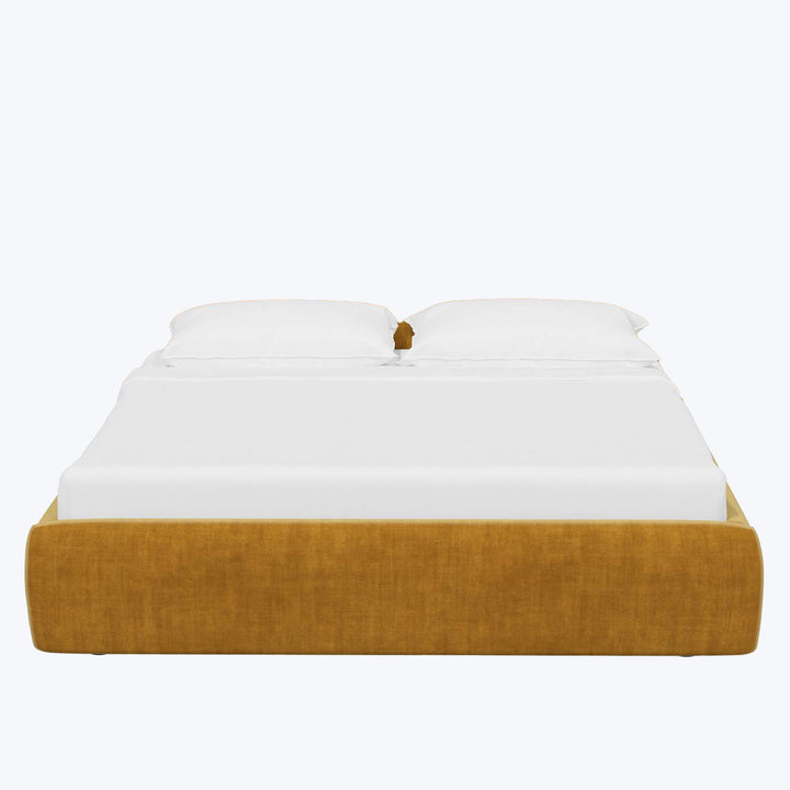 Mustard yellow upholstered bed frame with crisp white bedding.