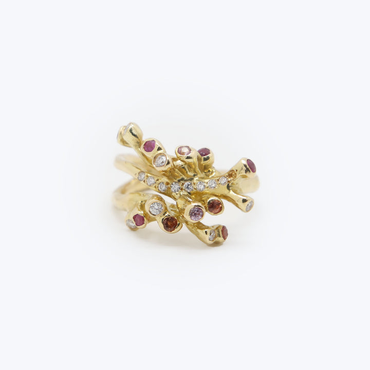 Luxurious gold ring with branching coral-like design and gemstones.