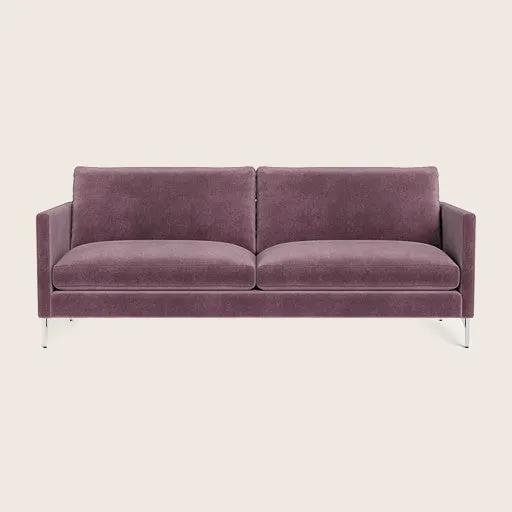 A purple two-seat sofa with sleek legs and slim track arms, upholstered in a velvet fabric.