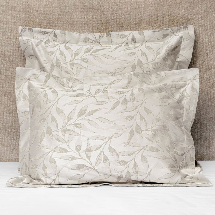 Two elegant leafy vine pattern pillows against textured beige backdrop.