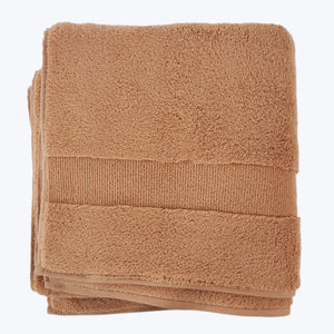 Neatly folded beige bath towel with decorative ribbed band detail. - hover