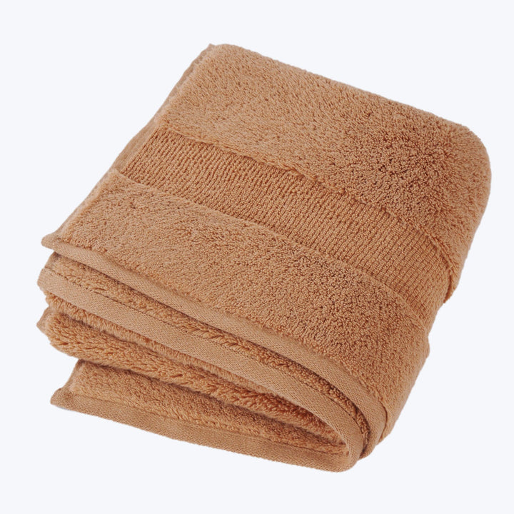 Folded brown bath towel with decorative pattern on plush texture.