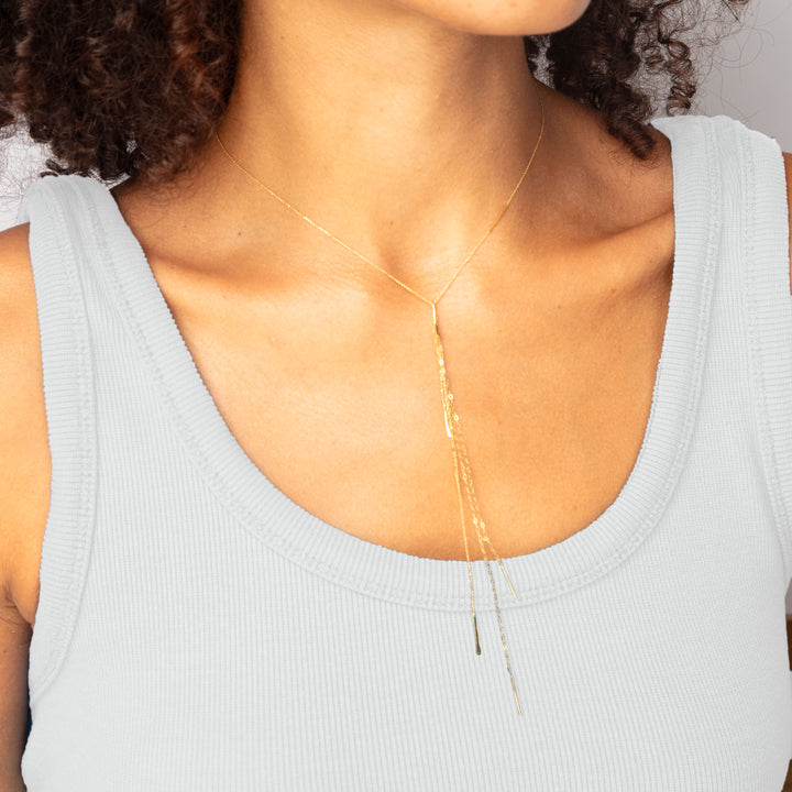 Close-up of person with curly hair wearing gold necklace accessory.